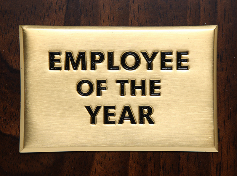 Detail close up of a CNC engraved brass plate with V-carved black-filled lettering showing the classic trophy plate appearance
