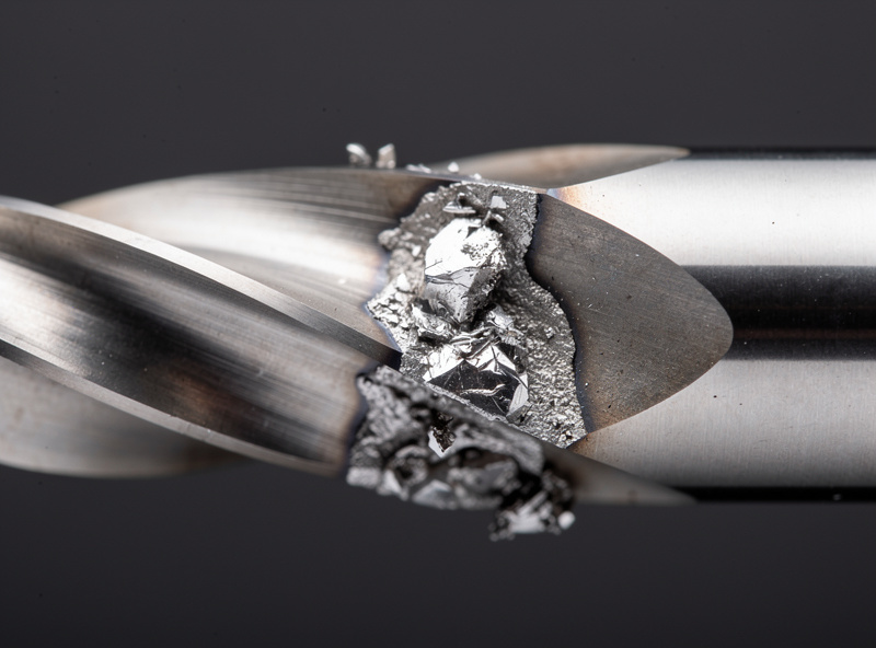 Macro view of a CNC end mill with visible built up edge and chip welding aluminum residue showing the failure mode caused by inadequate lubrication