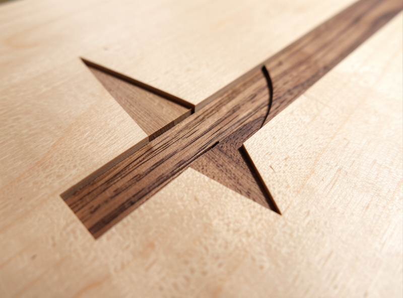 Contrasting maple and walnut V-carve inlay seated and flush-sanded on a finished CNC panel