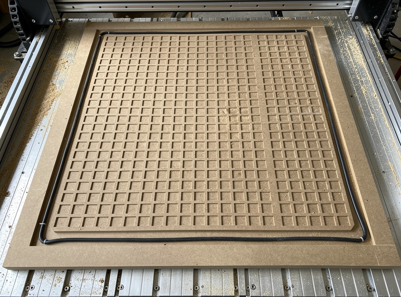 DIY MDF vacuum table with a milled grid pattern and gasket channel on a CNC machine bed