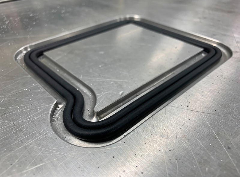 Gasket cord seated in a routed channel framing a part footprint on a CNC vacuum table