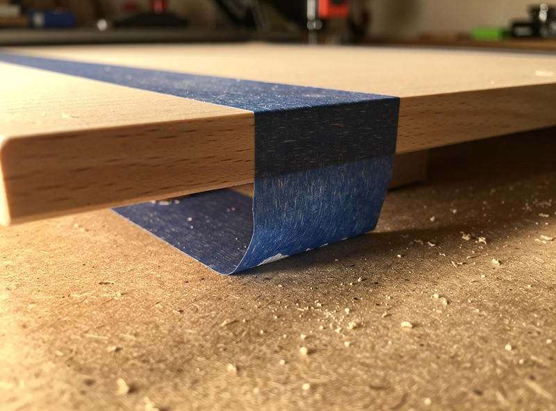 Painter's tape applied to a wood workpiece and to a CNC spoilboard, ready for CA glue between the layers