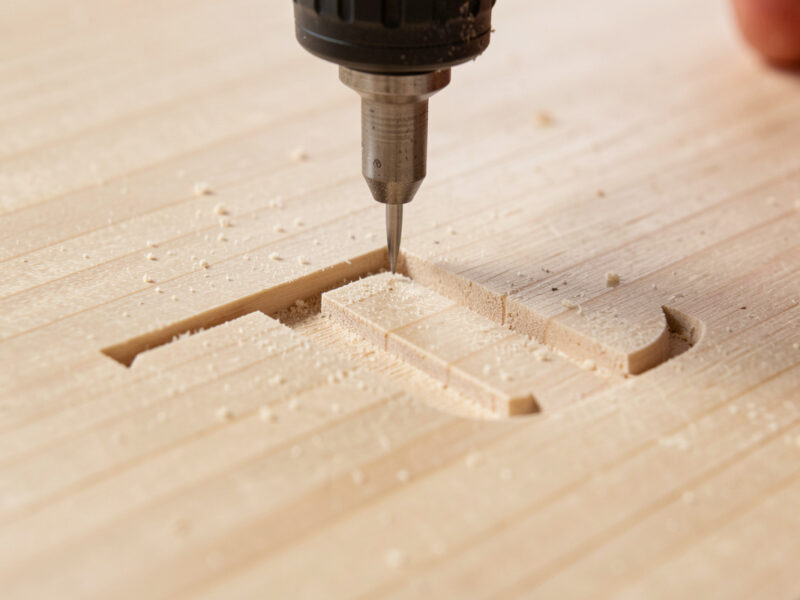 V-bit carving a sharp serif corner into a maple sign blank